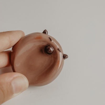 Objeta decorativo redondo castanho com olhos e orelhas pequenas