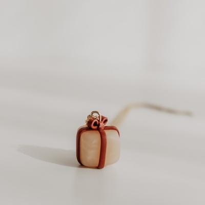 Pendente pequeno em forma de caixa de presente com laço vermelho e grampo dourado