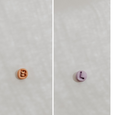 Dois botões redondos com letras 'B' e 'L' nas cores salmão e lilás sobre fundo claro