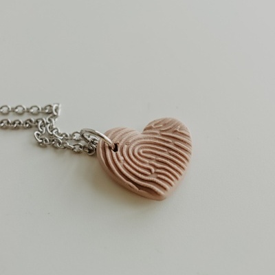 Colar com pendente em forma de coração castanho com textura de impressão digital.