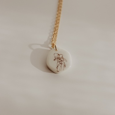 Colar com pendente redondo branco com desenho de casal a abraçar