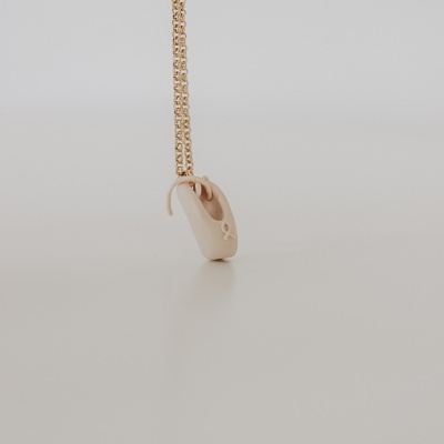 Colar dourado com pendente em forma de cadeado numa superfície branca