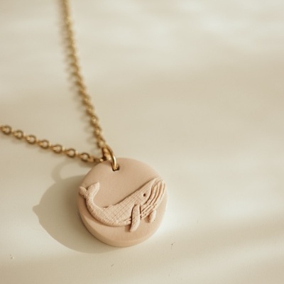 Colar dourado com pendente bege em forma de baleia