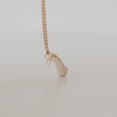 Colar com pendente de sapato de salto alto beige em fundo branco