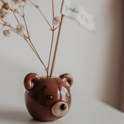 Vaso cerâmico castanho em forma de cabeça de urso com ramos secos