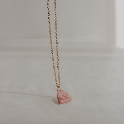 Colar dourado com pendente cor-de-rosa em forma de coração com relevo