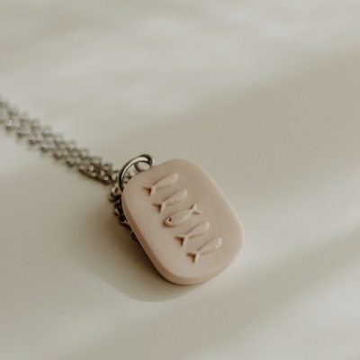 Colar com pendente creme com peixinhos gravados e corrente prateada