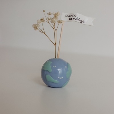 Vaso planeta azul com flores secas e bandeira branca com texto