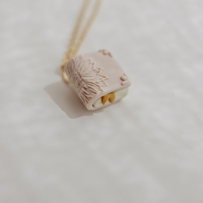 Colar com pendente de flor rosa claro com detalhes amarelos e corrente dourada