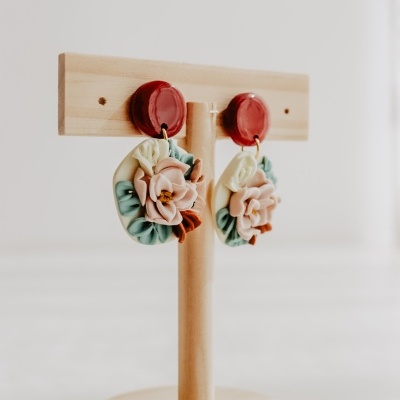 Brincos florais coloridos em suporte de madeira claro