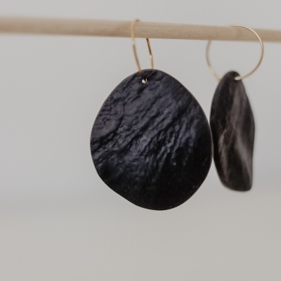 Brincos pretos texturizados pendurados em gancho dourado