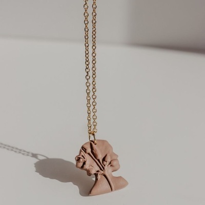 Colar com pendente em forma de rosto estilizado rosa claro e corrente dourada