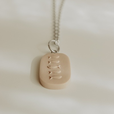 Colar com pendente retangular com desenho de cinco peixes em relevo