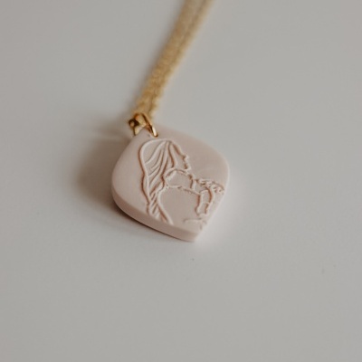 Colar com pendente rosa claro e figura gravada de mulher e criança, corrente dourada