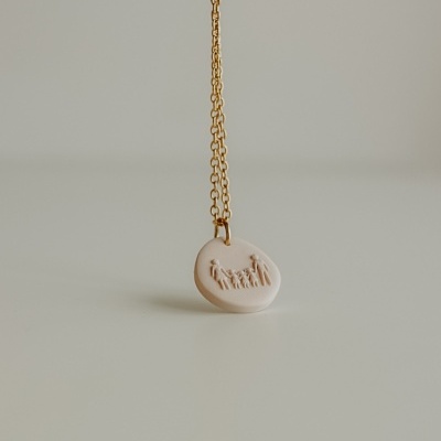 Colar dourado com pendente creme em relevo de família