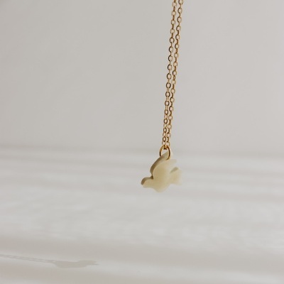 Colar dourado com pendente de pássaro branco