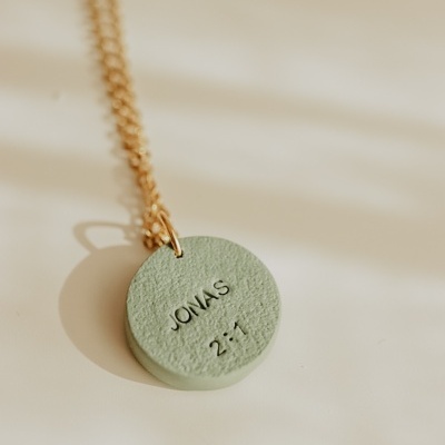 Colar dourado com pendente redondo verde gravado com texto