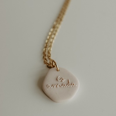 Colar dourado com pendente branco de cerâmica com inscrição é s amada