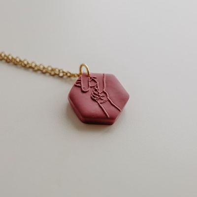 Colar com pendente hexagonal vermelho escuro com relevo floral em corrente dourada