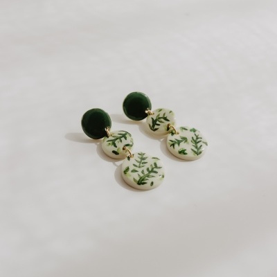 Brincos verdes e brancos com padrão de folhagem em fundo branco