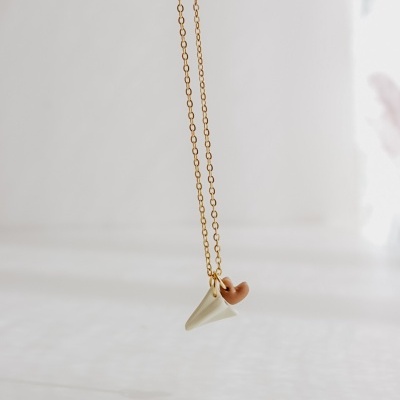 Colar dourado com pendente de cone branco e anel castanho