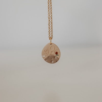 Colar com pendente redondo em metal dourado com astronauta e cacto em relevo