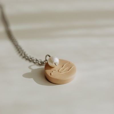 Colar com pendente redondo bege com relevo e bola branca texturada