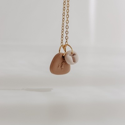 Colar dourado com pendentes castanho e branco suspensos