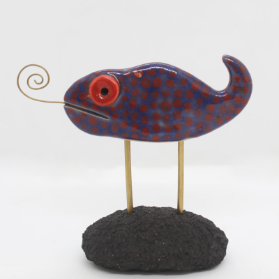 Estatueta decorativa de peixe azul e vermelho em base preta.