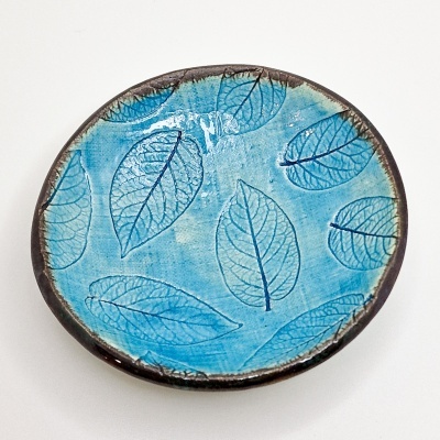 Prato redondo de cerâmica azul com padrão de folhas