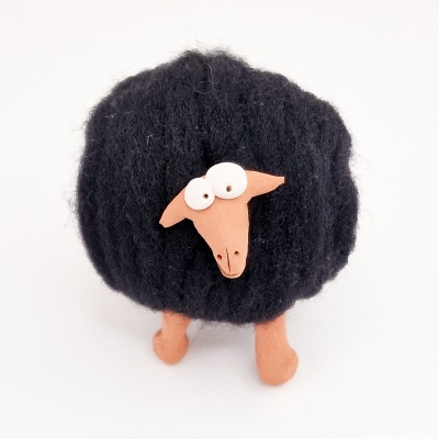 Boneco de ovelha peludo preto com cabeça e patas castanhas