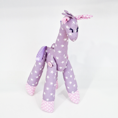 Boneco girafa de peluche lilás com estrelas e detalhes rosa, fundo branco
