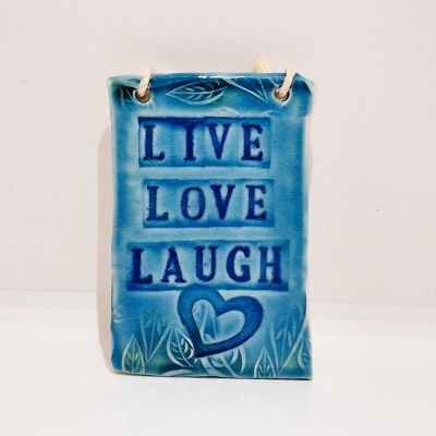 Placa decorativa azul com as palavras LIVE, LOVE, LAUGH e um coração