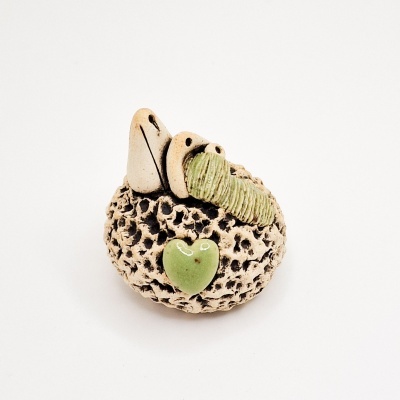 Escultura pequena em cerâmica bege com textura porosa e detalhes verdes