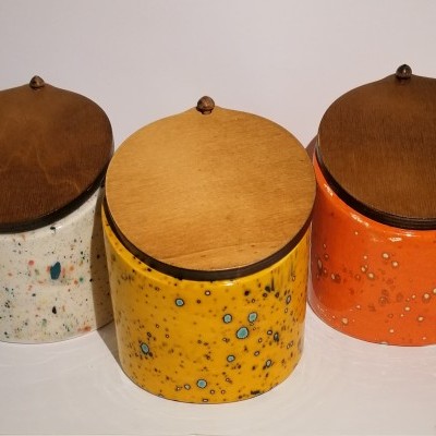Três potes de cerâmica coloridos com tampas de madeira