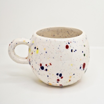 Caneca de cerâmica branca com pintas coloridas e asa circular