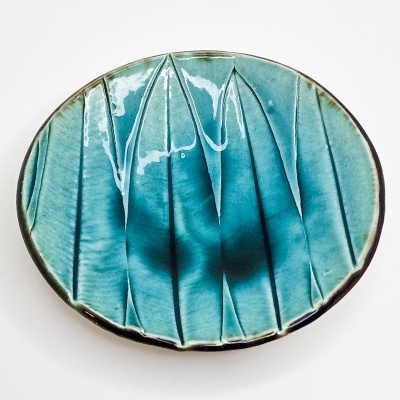 prato redondo em cerâmica azul e verde com padrão de folhas