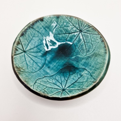 Prato cerâmico redondo com padrão de folhas azuis e verdes