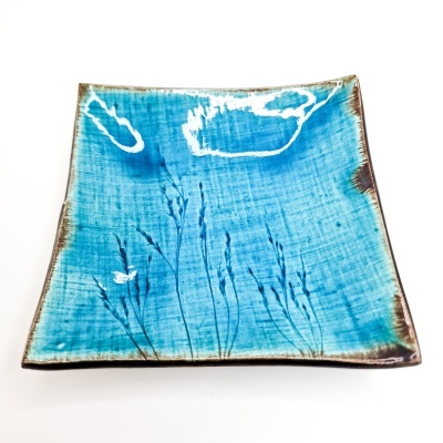 Prato quadrado azul de cerâmica com padrão de plantas e bordas castanhas