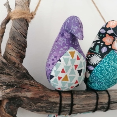 Dois pássaros de tecido coloridos sobre madeira rústica