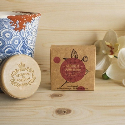 Sabonete Jasmim Branco em embalagem de papel kraft com vaso azul decorativo e tampa redonda Esências de Portugal sobre madeira