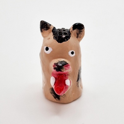 Figura de cerâmica castanha e preta em forma de cão com língua vermelha