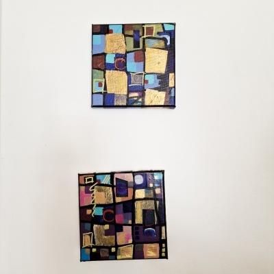 Duas pinturas abstratas quadradas com blocos coloridos na parede branca