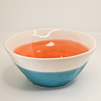 Tigela cerâmica tricolor com interior laranja, exterior branco e azul.