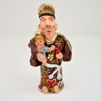 Estatueta cerâmica de santo com criança, vestido castanho e detalhes coloridos