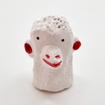 Figura decorativa branca de cabeça de macaco com detalhes vermelhos