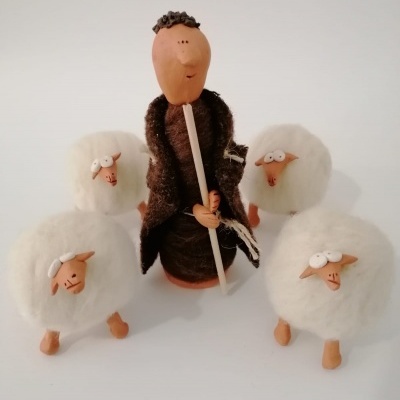 Boneco pastor com cajado rodeado por quatro ovelhas brancas