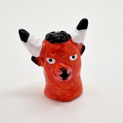 Pequena escultura de cabeça de touro laranja com chifres brancos e pretos