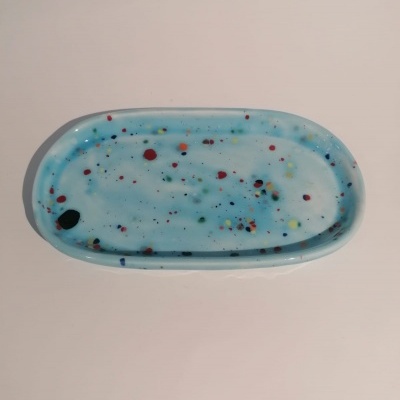 Tabuleiro oval azul claro com manchas coloridas sobre superfície branca