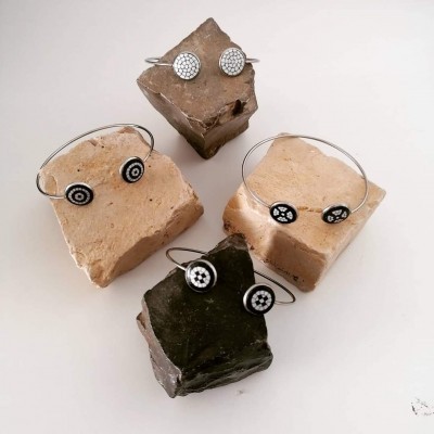 Pulseiras prateadas com padrões em preto e branco sobre pedras